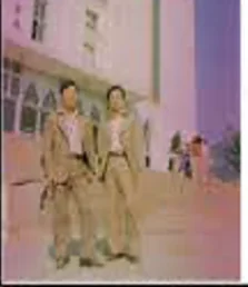 Faded colour photo of two men in suits standing on steps in front of a white building with arched windows.
